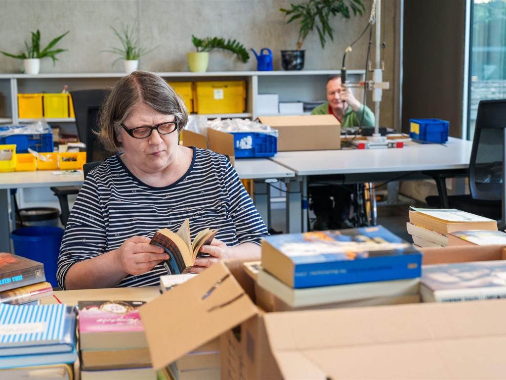 Man sieht eine Frau, welche in einem Buch blättert.